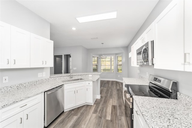 kitchen featuring sink, white cabinetry, hanging light fixtures, stainless steel appliances, and kitchen peninsula