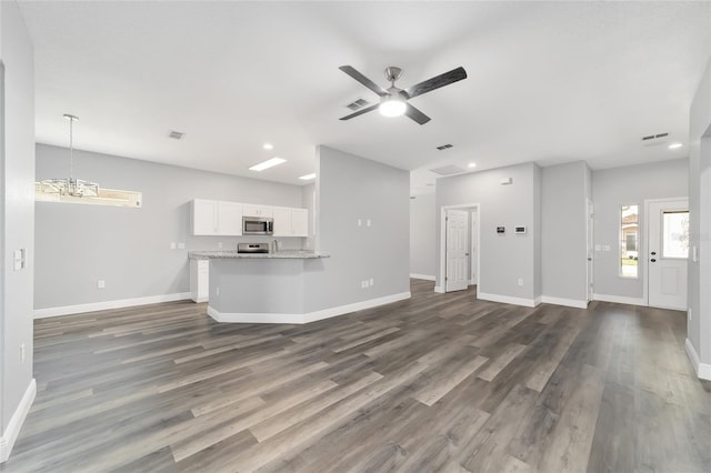 unfurnished living room featuring dark wood-type flooring and ceiling fan