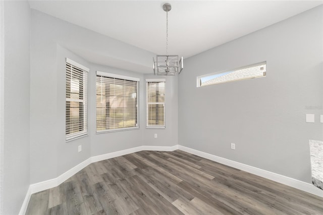 unfurnished room featuring wood-type flooring and a notable chandelier