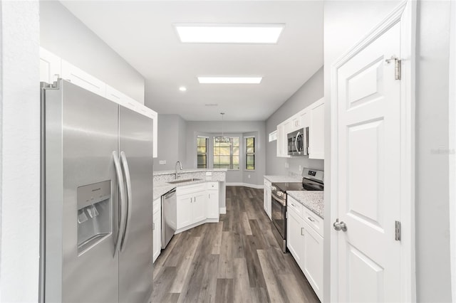 kitchen with sink, light stone counters, appliances with stainless steel finishes, kitchen peninsula, and white cabinets