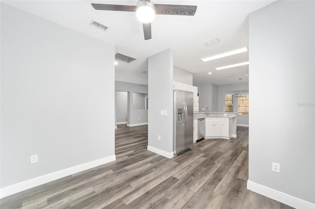 kitchen with sink, wood-type flooring, hanging light fixtures, appliances with stainless steel finishes, and white cabinets