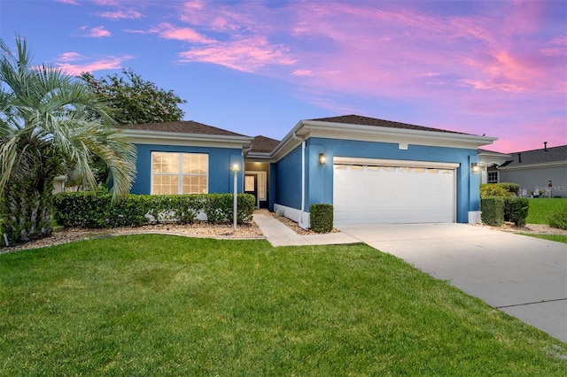 ranch-style house featuring a garage and a yard