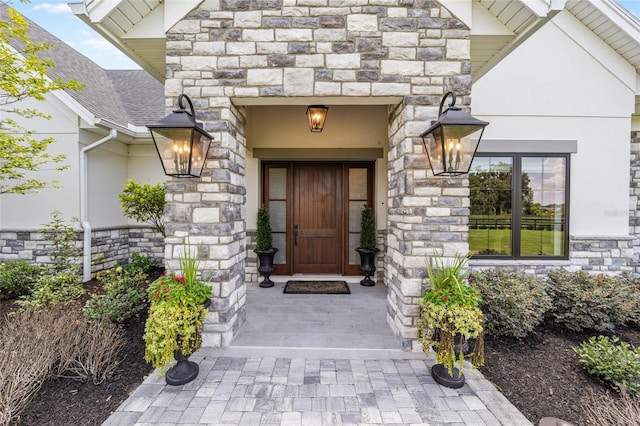 property entrance with stone siding, roof with shingles, and stucco siding