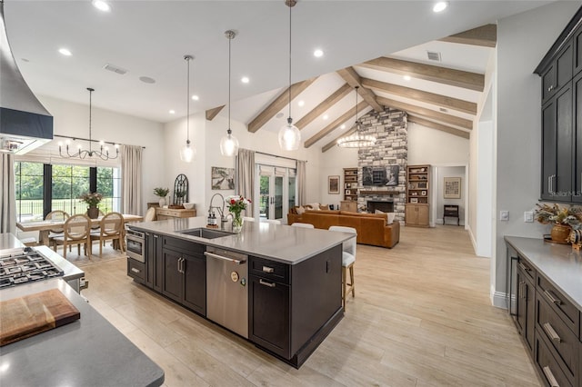 kitchen featuring a notable chandelier, a fireplace, a sink, visible vents, and stainless steel dishwasher