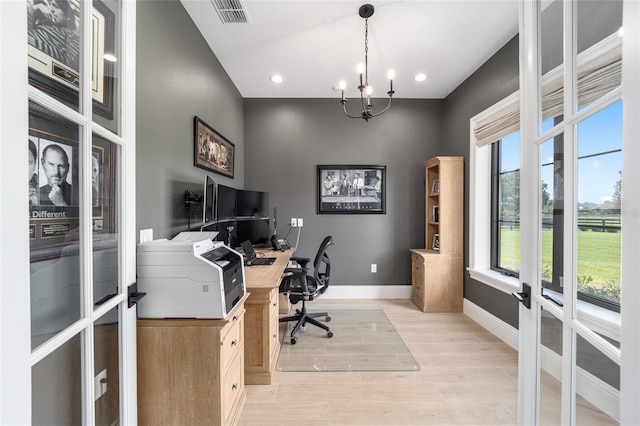 office with light hardwood / wood-style flooring, plenty of natural light, and a notable chandelier