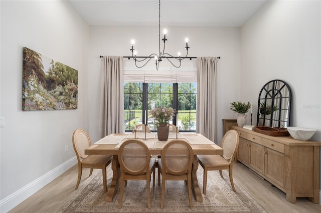 dining area with light wood-type flooring and an inviting chandelier