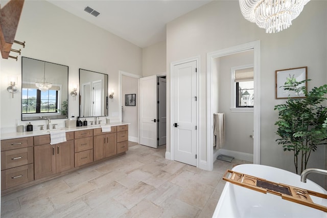 full bath featuring double vanity, a soaking tub, a wealth of natural light, and a notable chandelier