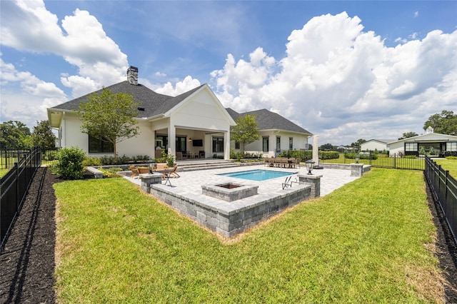 rear view of property with a lawn, a patio area, and a fenced in pool