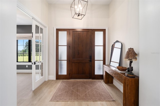 entrance foyer with light hardwood / wood-style floors, french doors, and a chandelier