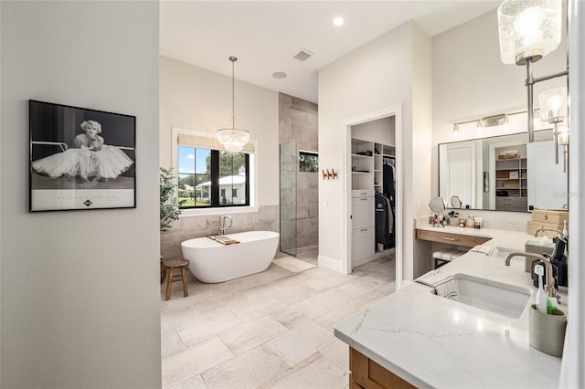 bathroom with vanity, separate shower and tub, tile walls, and an inviting chandelier