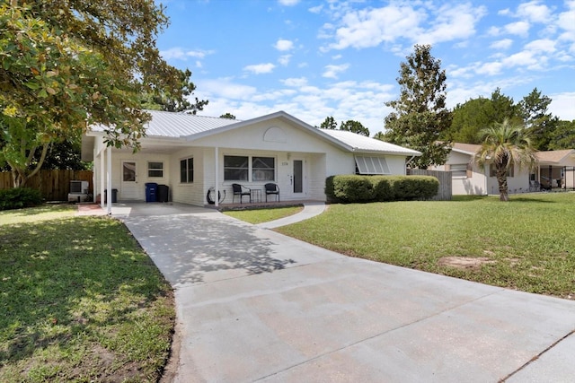 ranch-style home featuring fence, a front yard, metal roof, a carport, and driveway