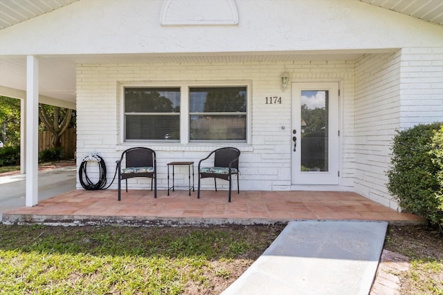 doorway to property featuring brick siding and a patio area