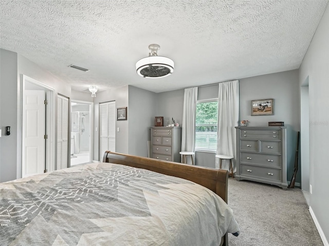 carpeted bedroom with a textured ceiling, visible vents, and baseboards