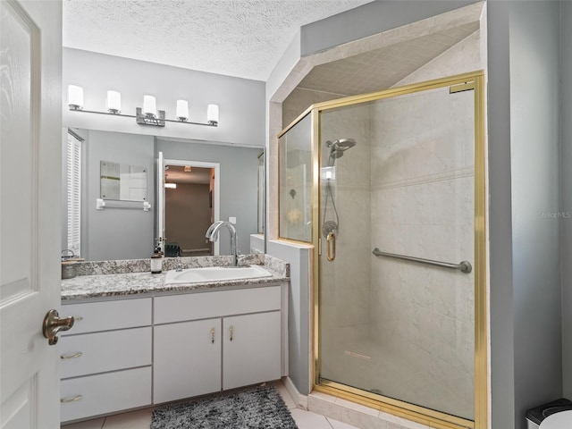 bathroom featuring a textured ceiling, tile patterned flooring, a shower stall, and vanity