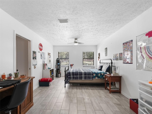 bedroom featuring a textured ceiling, wood finish floors, a ceiling fan, and baseboards