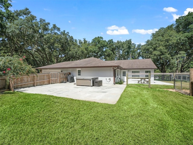 rear view of house with a hot tub, a patio, a fenced backyard, a yard, and stucco siding