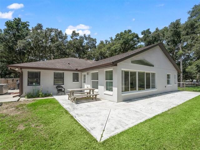 rear view of property featuring a patio area, fence, stucco siding, and a yard