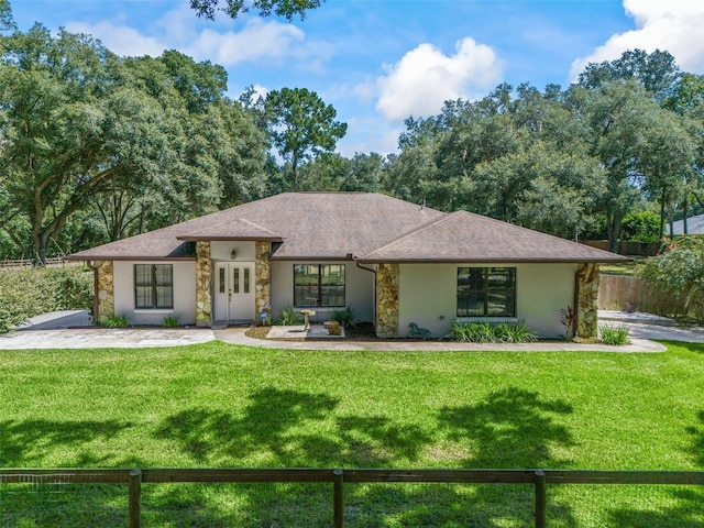 view of front of home with a shingled roof, fence, and a front yard