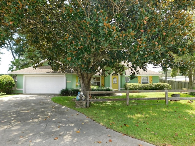 view of property hidden behind natural elements featuring a garage and a front lawn