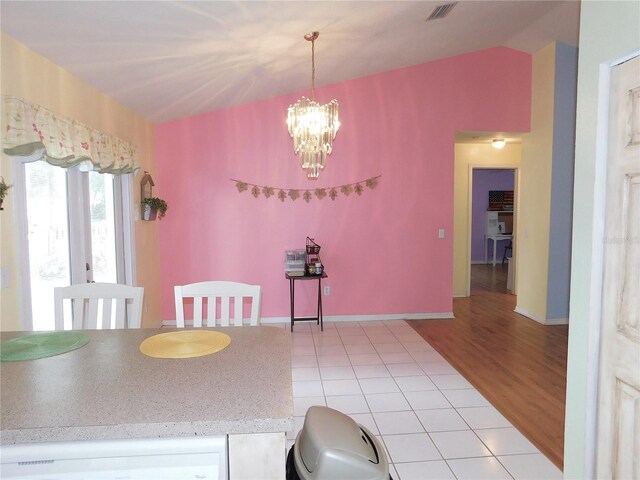 dining space with lofted ceiling, a notable chandelier, and light tile patterned floors