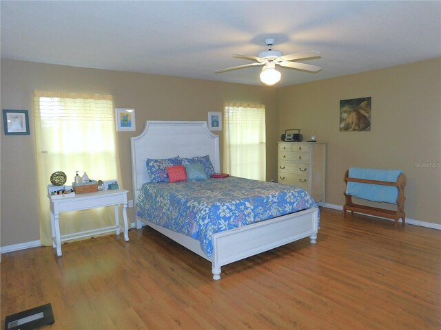 bedroom featuring multiple windows, ceiling fan, and hardwood / wood-style floors