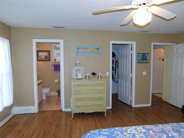 bedroom with a spacious closet, a closet, connected bathroom, dark hardwood / wood-style floors, and ceiling fan