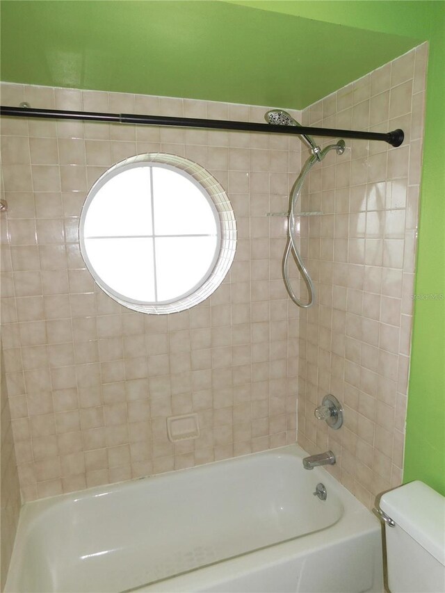 bathroom with tiled shower / bath combo and toilet