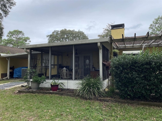 rear view of property with a lawn and a sunroom