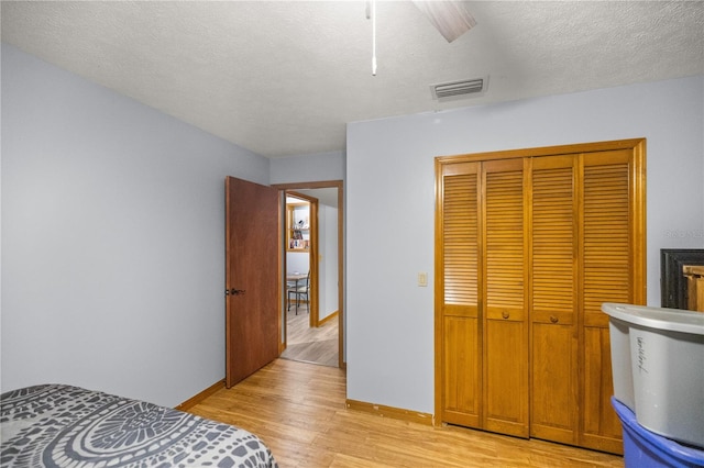 bedroom featuring a textured ceiling, ceiling fan, a closet, and light wood-type flooring