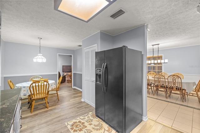 kitchen with a textured ceiling, an inviting chandelier, black refrigerator with ice dispenser, pendant lighting, and light wood-type flooring