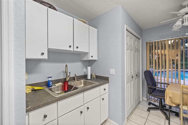 kitchen with white cabinets, light tile patterned floors, sink, ceiling fan, and a textured ceiling