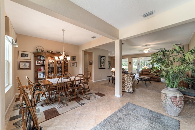 tiled dining space with ceiling fan with notable chandelier