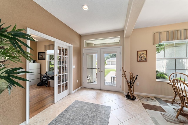 doorway to outside with a textured ceiling, french doors, and light tile patterned flooring