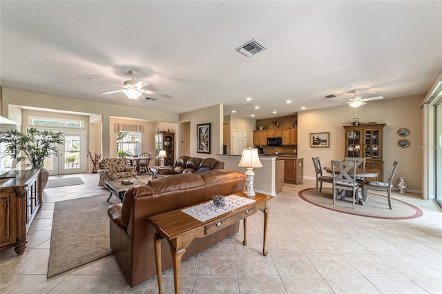 living room featuring a textured ceiling, ceiling fan, and light tile patterned floors