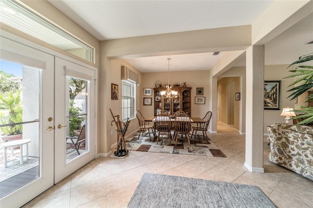 tiled dining area featuring an inviting chandelier and french doors