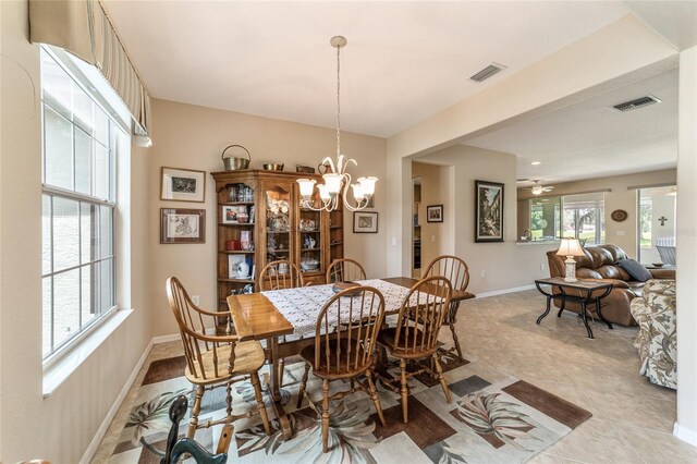 tiled dining room featuring ceiling fan with notable chandelier