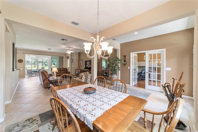 tiled dining space with ceiling fan with notable chandelier and french doors