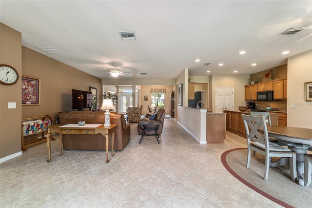 tiled living room with ceiling fan and sink