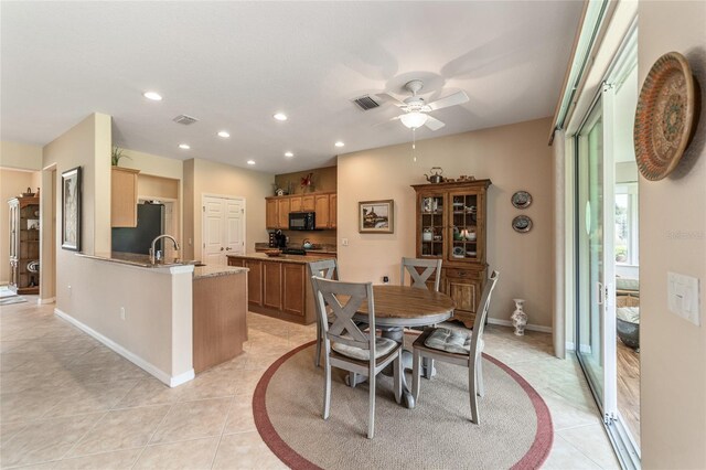 tiled dining space featuring ceiling fan and sink