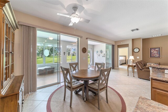 dining area with ceiling fan, light tile patterned floors, and a textured ceiling