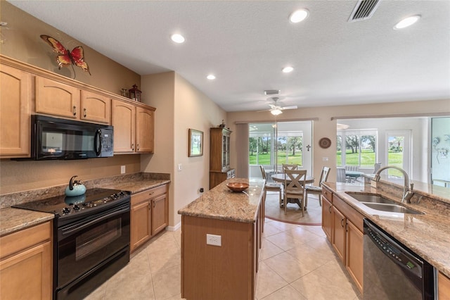 kitchen featuring black appliances, a center island, sink, ceiling fan, and light stone counters