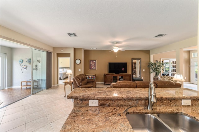 tiled living room with ceiling fan, a textured ceiling, and sink