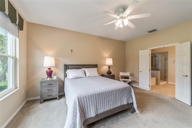 carpeted bedroom featuring multiple windows, connected bathroom, and ceiling fan