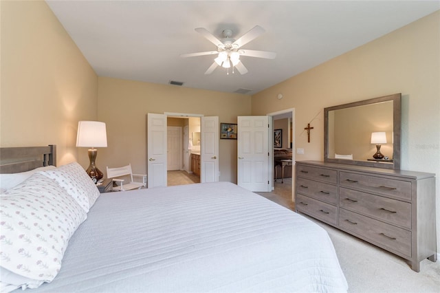 bedroom featuring light carpet, ensuite bathroom, and ceiling fan