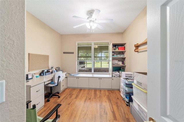 home office featuring built in desk, ceiling fan, and light hardwood / wood-style flooring