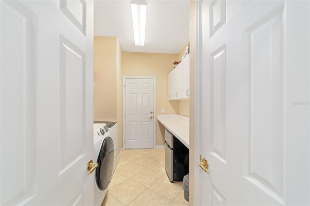 clothes washing area featuring cabinets, washing machine and dryer, and light tile patterned flooring