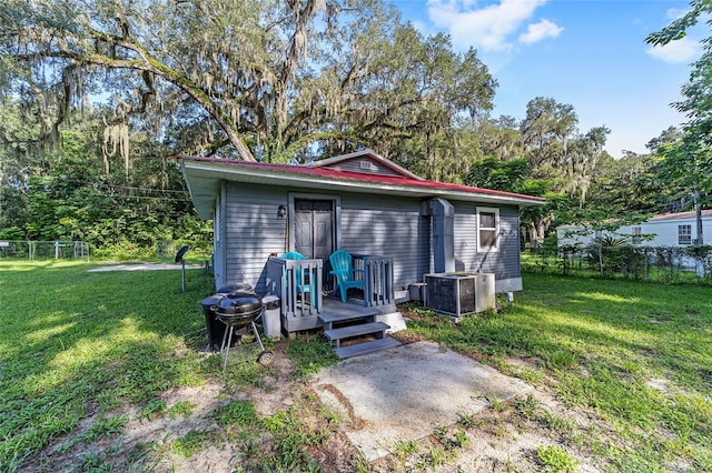 rear view of property with central air condition unit, a lawn, and a wooden deck