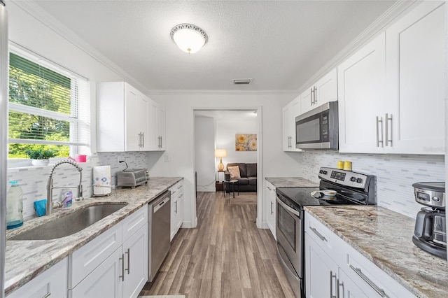 kitchen with sink, stainless steel appliances, light stone countertops, and white cabinetry