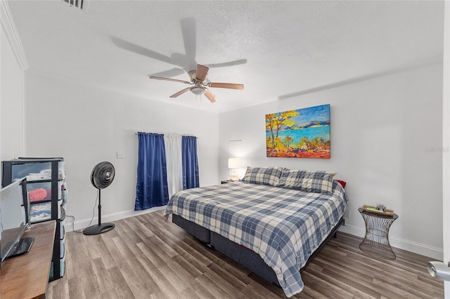 bedroom with a textured ceiling, ceiling fan, crown molding, and dark wood-type flooring