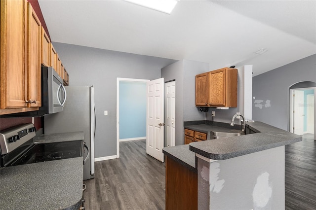 kitchen featuring sink, a breakfast bar area, kitchen peninsula, stainless steel appliances, and dark wood-type flooring